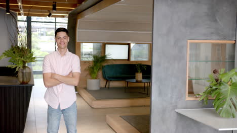 smiling man standing with arms crossed in modern office lobby area, copy space