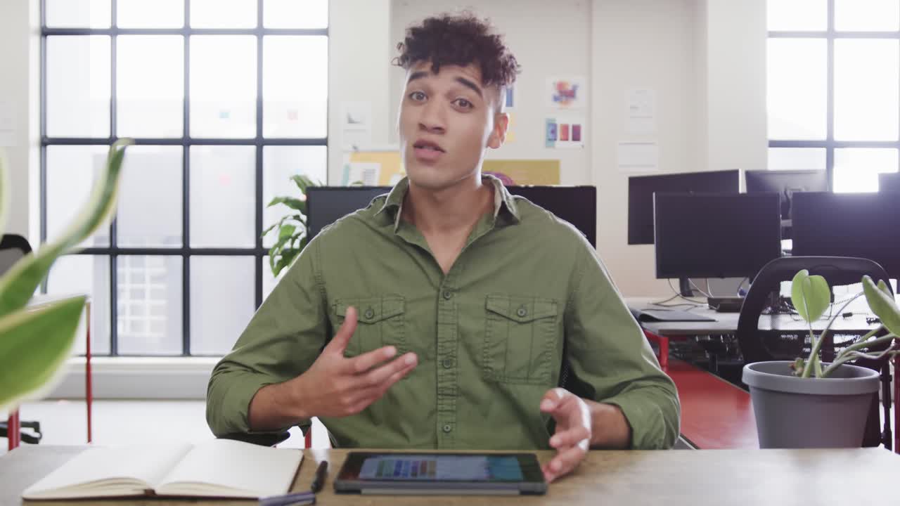 Portrait of biracial male designer in video call at computer in casual office, slow motion