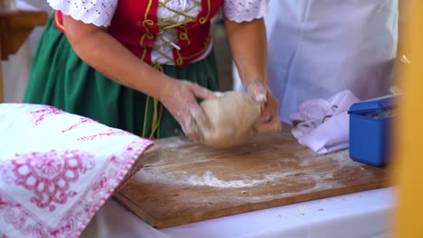 traditional baker kneading dough on a wooden board during a cultural event