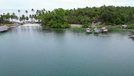 Aerial-pan-across-bangka-docked-at-wooden-huts-on-stilts,-balabac-islands