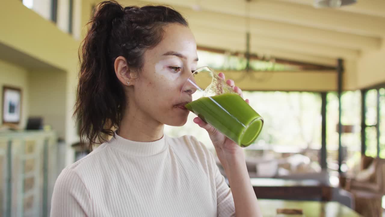 Donna birazziale rilassata con vitiligine che beve un frullato salutare in cucina