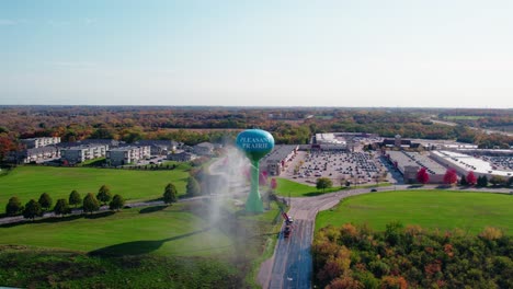 Elevated-view-of-a-utility-vehicle-power-washing-a-water-tower,-suburban-landscape-Pleasant-Prairie,-WI