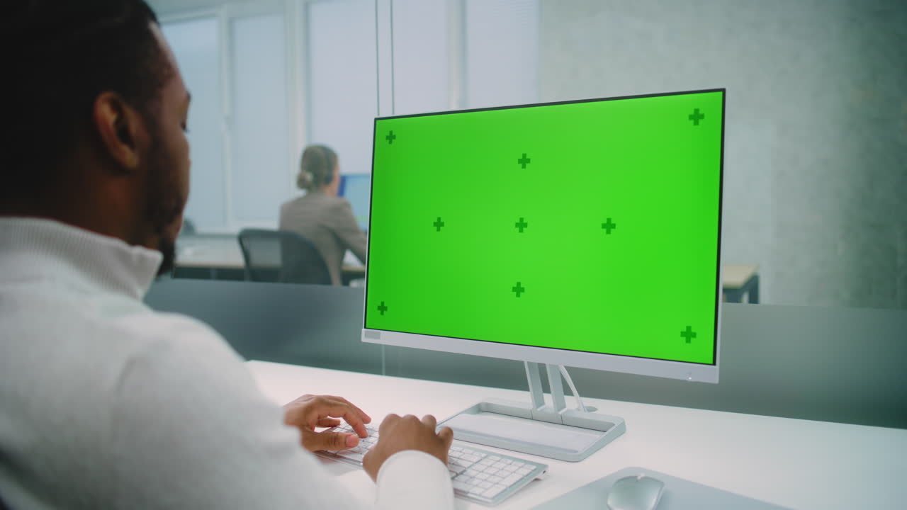 Man working on a computer with a green screen