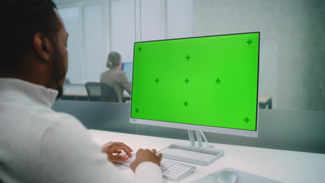 hombre trabajando en una computadora con una pantalla verde