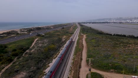 commuter train running on rail track on mediterranean coast in megadim moshav, israel