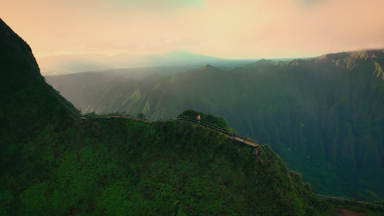 hombre corriendo en la escalera al cielo con un paisaje épico en el fondo, aéreo, hawaii