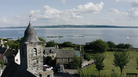 un avión no tripulado pasa junto a un campanario de una iglesia en culross, escocia.