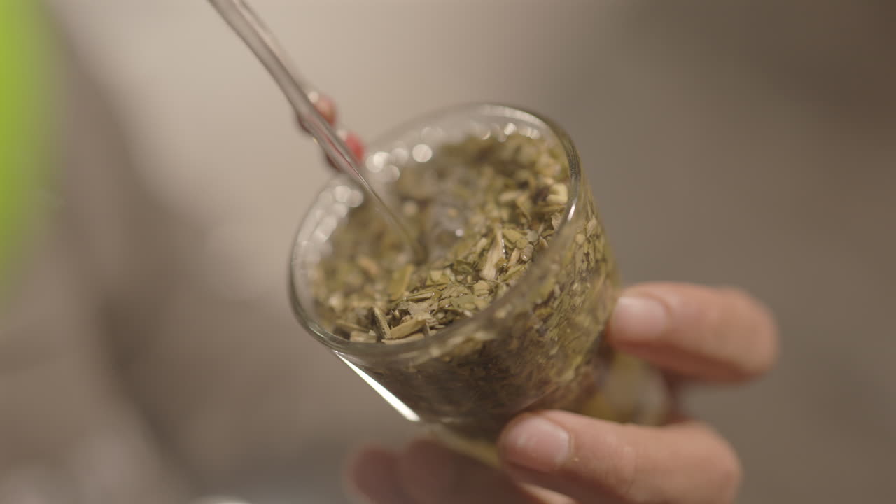 A close-up shot capturing water being poured into a mate gourd, ready for consumption.