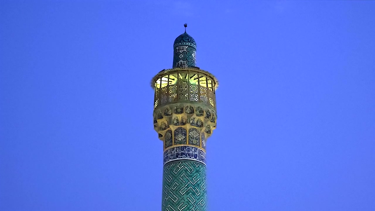 Illuminated Minaret of a Mosque Against a Clear Blue Sky