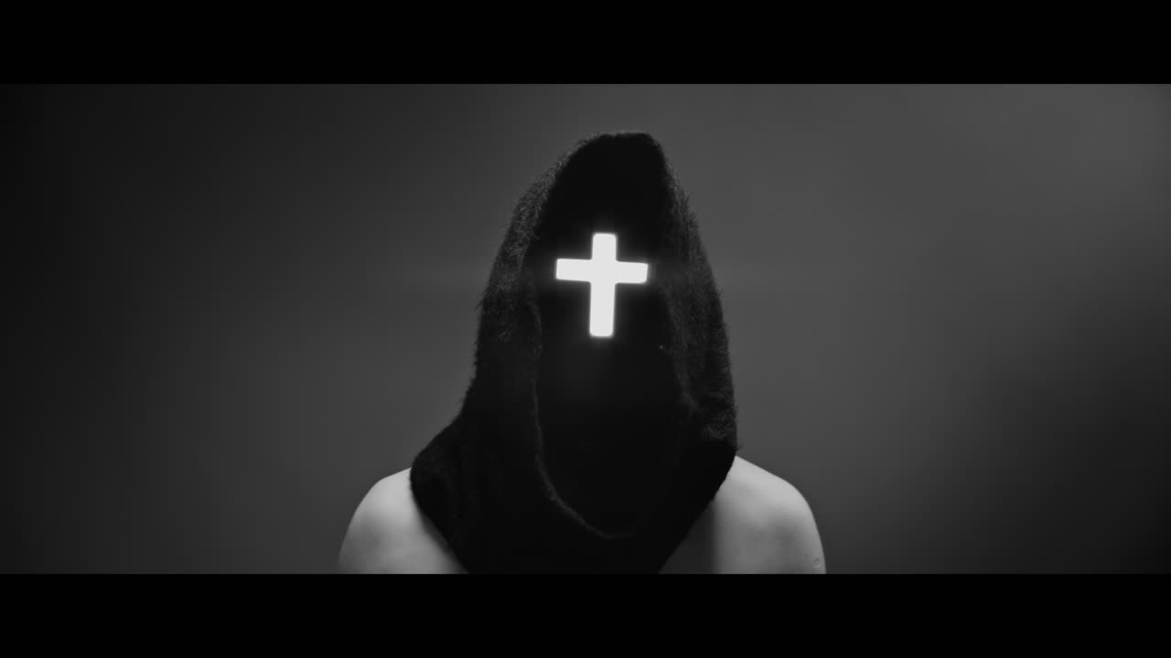 Masked and hooded man with cross of light glowing on his face rise his head