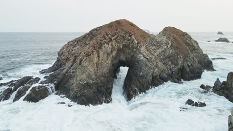 waves crashing through a rock arch in the ocean
