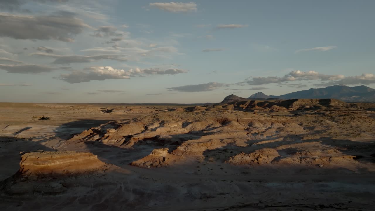 O pôr do sol projeta sombras sobre o terreno desértico acidentado - revelação aérea