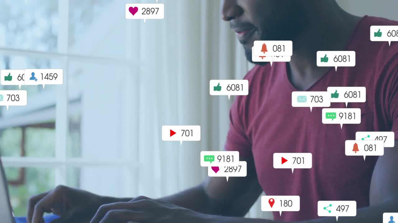 man typing on laptop by window, spawning social media icons grabbing smartphone, tracking metrics