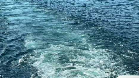 churning wake behind a ferry crossing blue sea, sunlight dancing on the water—great for motion, travel, or maritime visuals
