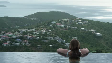 rear view of a girl relaxing in infinity pool and experiencing beautiful view of st