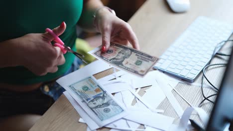 Person cutting up money with scissors on a desk