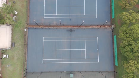 overhead bird's eye view drone shot of old tennis courts with different colours at a residential tennis club