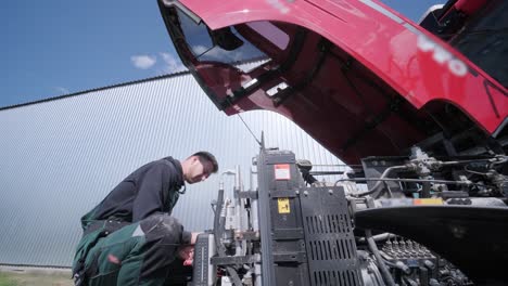 farmer mechanic repairing tractor. open tractor hood, engine. repair agricultural technology