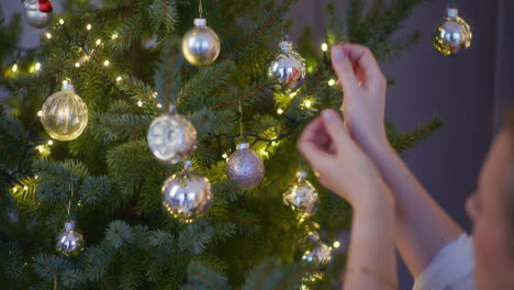 primer plano de la mano de la mujer decorando el árbol de navidad