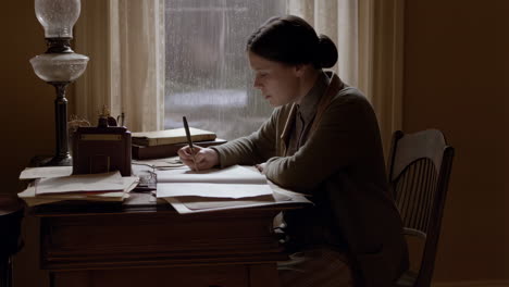 woman writing at a desk in a vintage setting