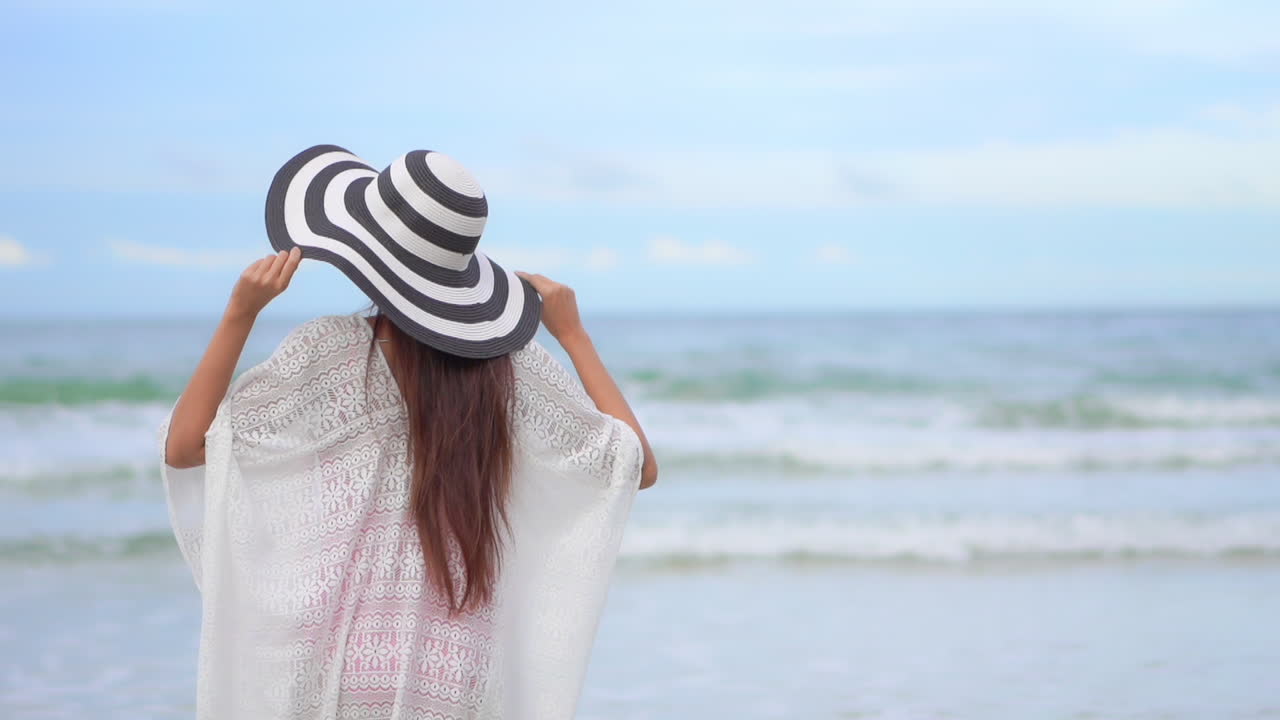 해변에서 바다를 향해 걷고 팔을 위로 올리는 아시아 여성 - 휴가 템플릿 백뷰