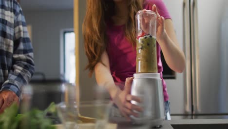 Senior-caucasian-father-and-teenage-daughter-preparing-health-drink-in-kitchen