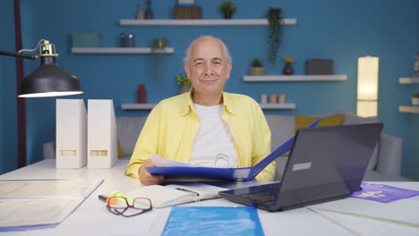 trabajador de oficina en el hogar anciano sonriendo a la cámara mirando el papeleo.