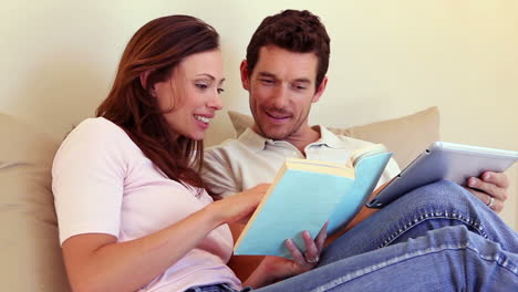 una pareja feliz sentada en el sofá usando una tableta juntos.