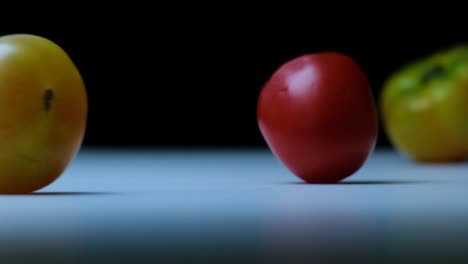 Slow-Motion-Shot-of-a-Variety-of-Tomatoes-Rolling-and-Bouncing-on-a-White-Surface