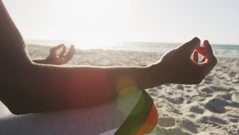 Sección-Media-De-Un-Hombre-Afroamericano-Practicando-Yoga-En-La-Playa,-Haciendo-Ejercicio-Al-Aire-Libre-Junto-Al-Mar.