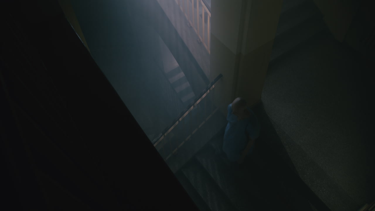 A bald man walks on the empty hospital staircase at night
