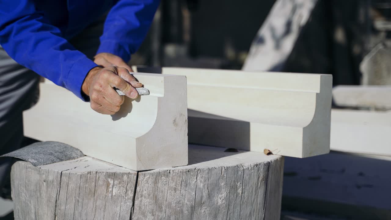 carpenter is polishing a wooden column in the courtyard in the street. Woodworking.