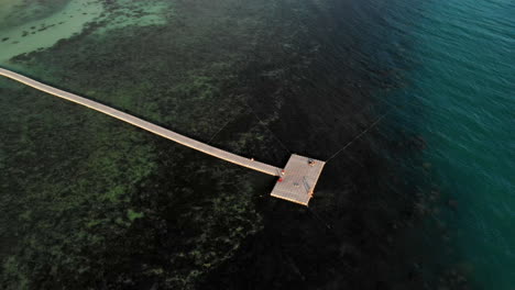 Drove-view-of-a-pier-above-corals-on-a-beach-in-Thailand