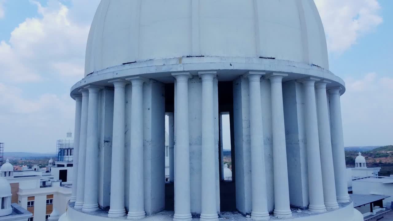 Cinematic aerial shot orbiting the majestic, columned dome of a neo-classical building in India, highlighting its grand architectural details against the sky. Perfect for of law, finance,