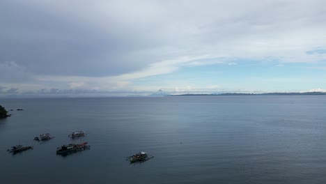 toma aérea cinemática inclinada hacia arriba de botes estabilizadores en la playa en la ciudad de bato, filipinas