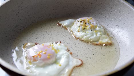 2 eggs frying in bubbling oil in frying pan