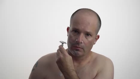 man shaving his face while facing camera in 60fps uhd.