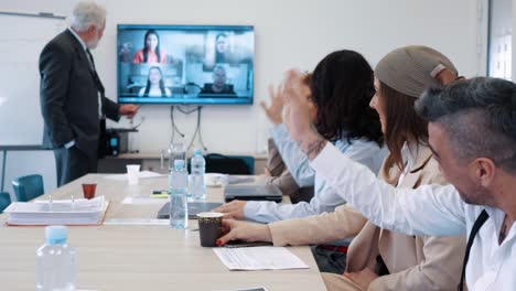 grupo de trabajadores de la empresa en una reunión de negocios saludando a sus colegas en una videoconferencia en la sala de reuniones