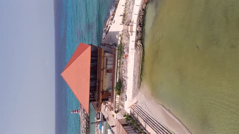 vertical orbit shot showing restaurante captain kidd la romana and caribbean sea in background - dominican republic in summer