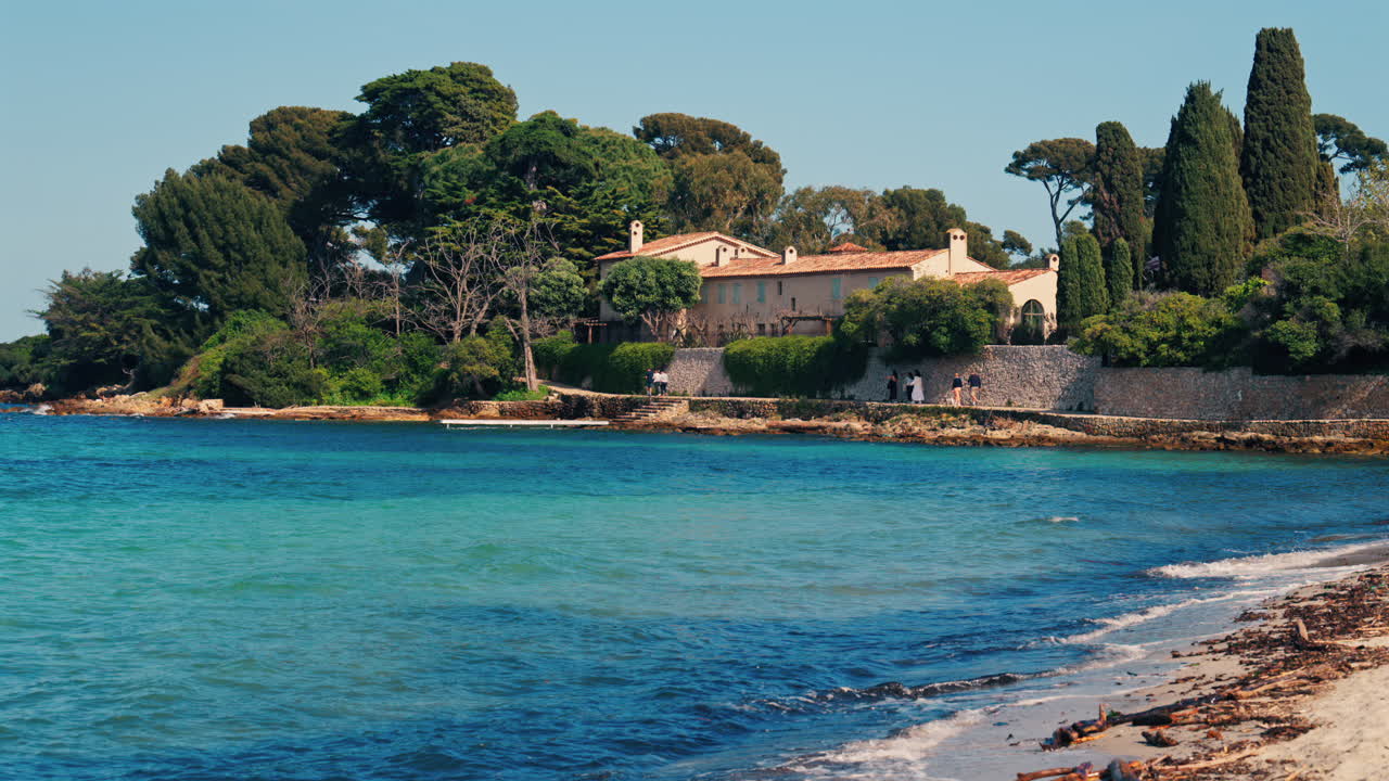 Distant view of multiple villas on the shore with the waves of the sea crashing on the rocks