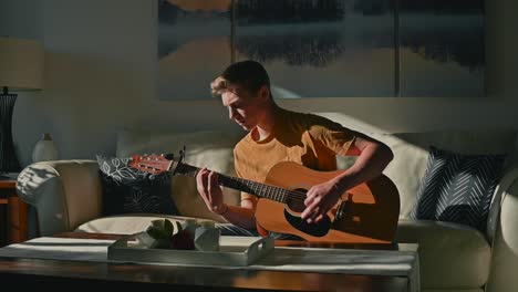 boy playing guitar on a couch