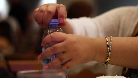manos abriendo una botella en un entorno público
