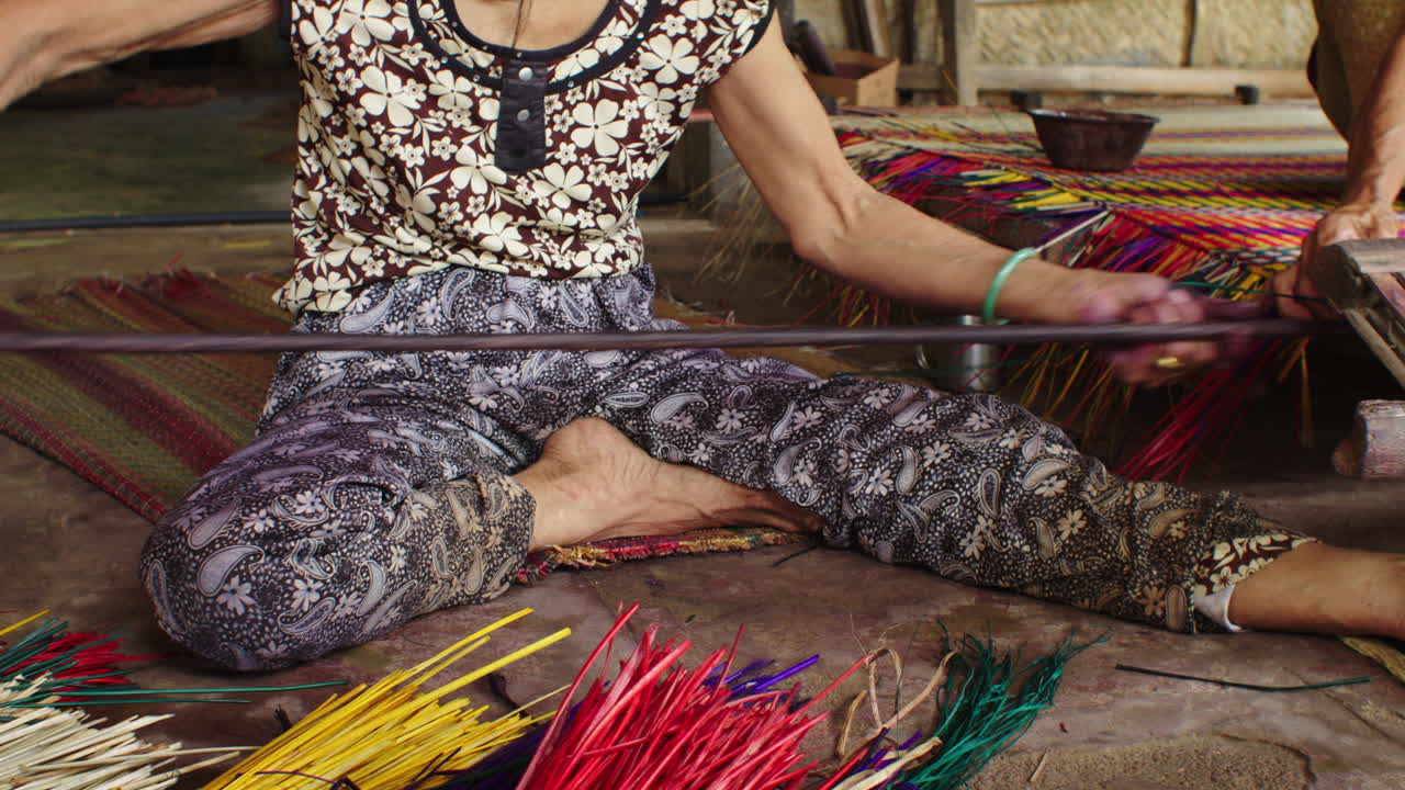 Mujer haciendo una alfombra con pajitas de colores.