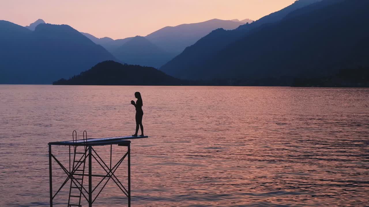 Cinematic shot of a child jumping in the water at sunset in Lombardy, Italy