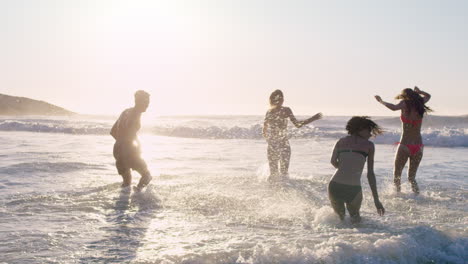 grupo diverso de amigos nadando en el mar al atardecer