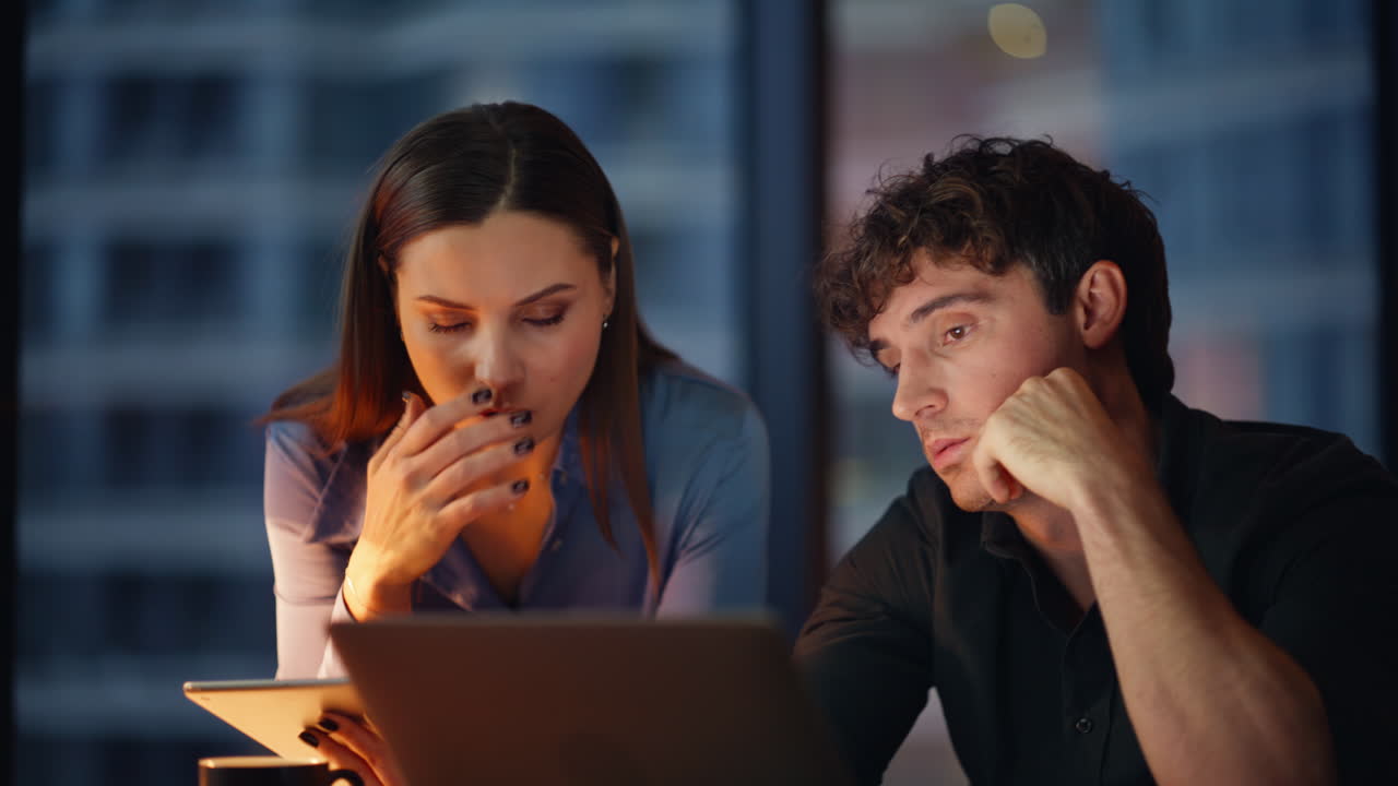 Woman helping sad colleague solving hard tasks at laptop overtime closeup