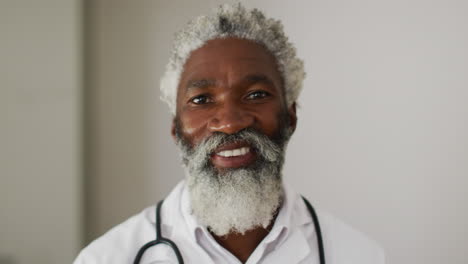 portrait of african american senior male doctor with white hair and beard smiling to camera