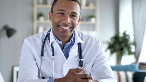 sonriente médico afroamericano positivo en el trabajo mirando a la cámara
