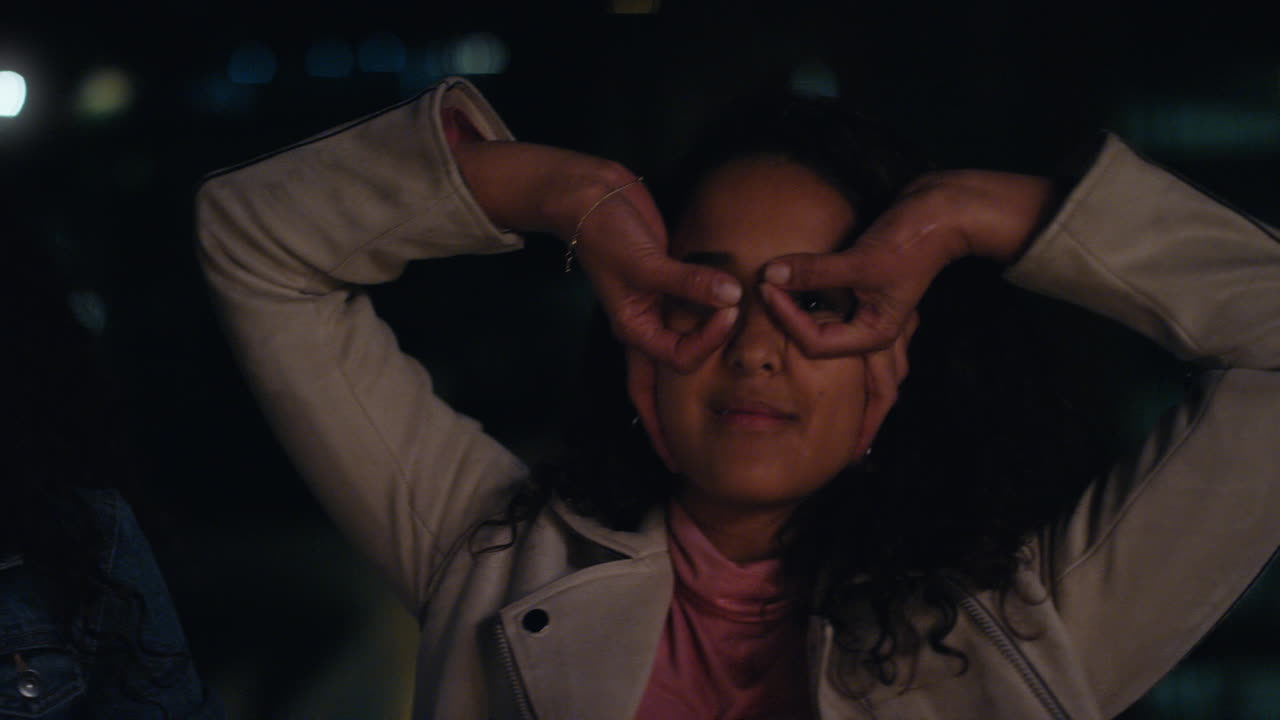 hermosas amigas haciendo caras en el techo por la noche divirtiéndose posando con expresiones tontas disfrutando de la vida nocturna urbana juntas luces de la ciudad bokeh en el fondo