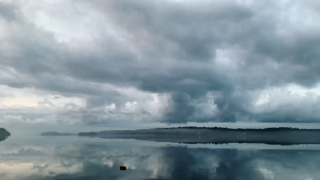 timelapse, islands in calm lake water with reflections of clouds and mist